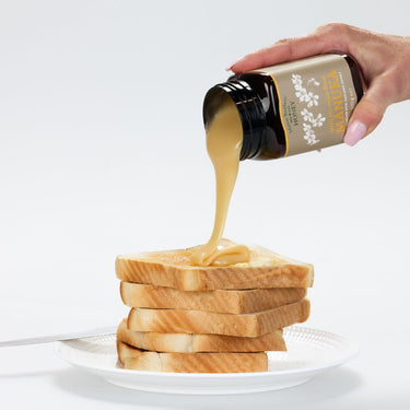 Pouring Mason Brothers Manuka Honey MGO50+ onto stack of bread